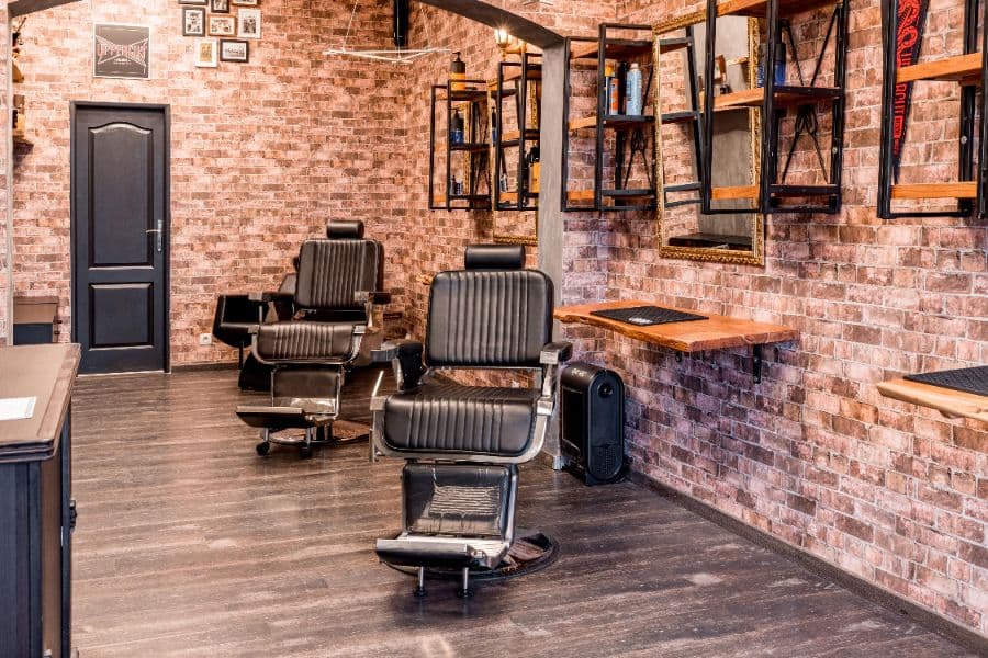 Barber chairs against an exposed brick wall inside Brickside Barbers